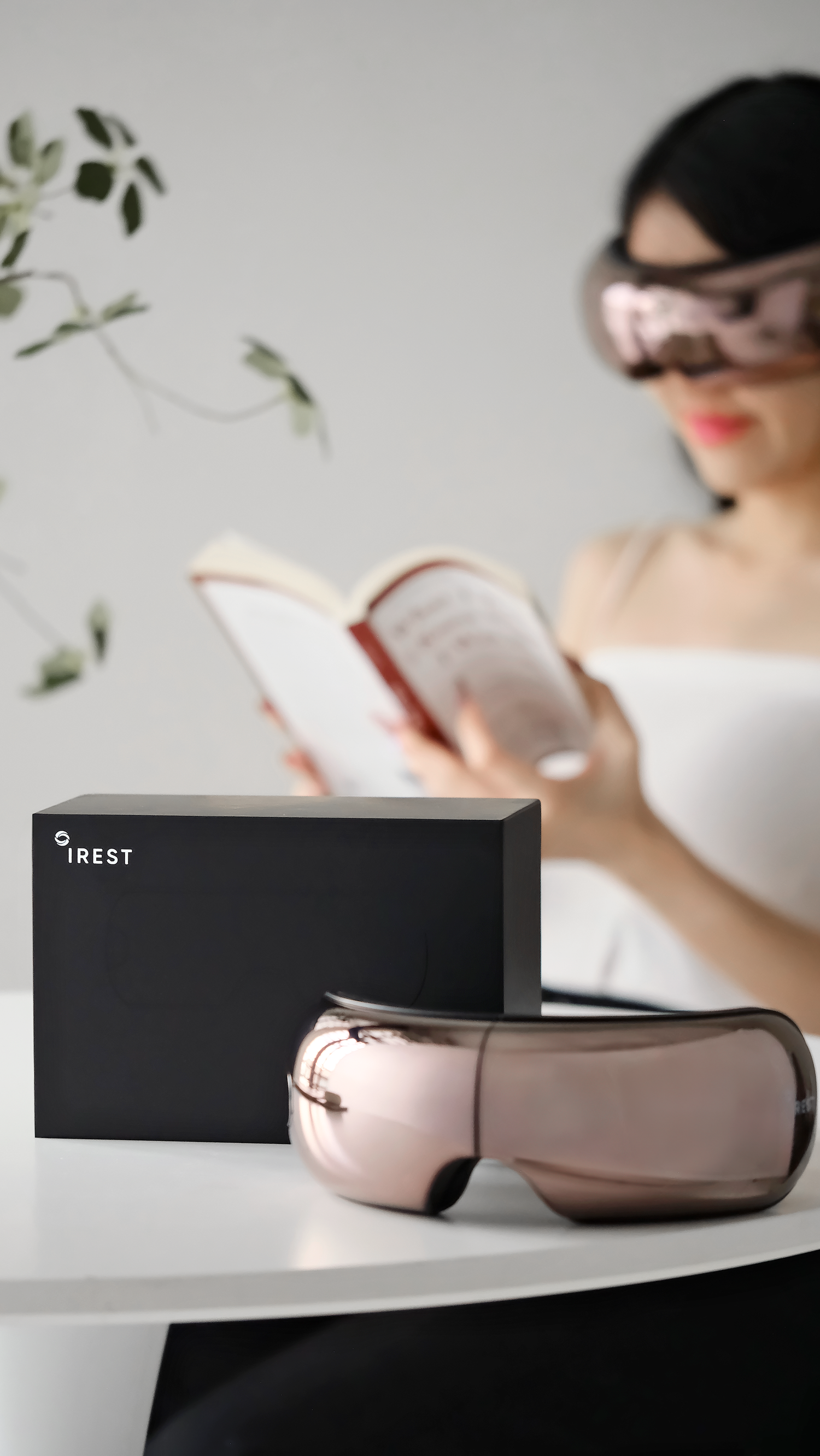 Lady flipping book wearing iREST EyeWell Relaxing Massager